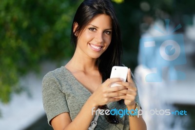 Smiling Beautiful Woman Texting With Her Phone In The Garden Stock Photo