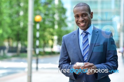 Smiling Businessman Holding Smartphone Stock Photo