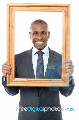 Smiling Businessman Looking Through Picture Frame Stock Photo