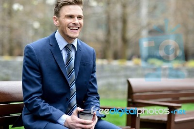 Smiling Businessman Relaxing On Park Bench Stock Photo