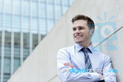 Smiling Businessman Standing Against Wall Stock Photo