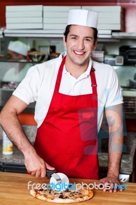 Smiling Chef Cutting Pizza With Cutter Stock Photo