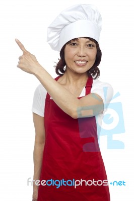 Smiling Female Chef Pointing Up Stock Photo