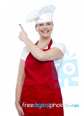 Smiling Female Cook Pointing Up Stock Photo