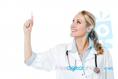 Smiling Female Doctor Pointing Upwards Stock Photo