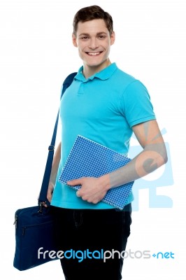 Smiling Guy Holding Notepad And Laptop Bag Stock Photo