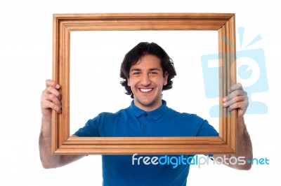 Smiling Guy Looking Through Picture Frame Stock Photo