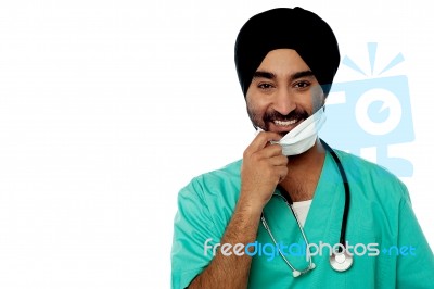 Smiling Male Doctor Removing Surgical Mask Stock Photo