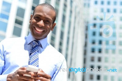 Smiling Male Executive Using His Mobile Phone Stock Photo