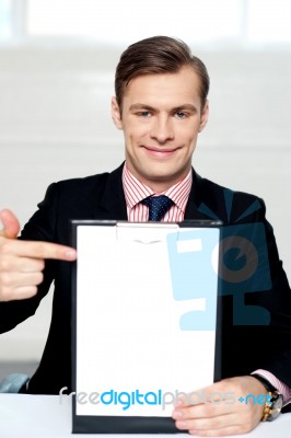 Smiling Man Pointing Towards Blank Clipboard Stock Photo