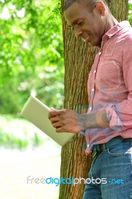 Smiling Man Using Tablet Pc In The Park Stock Photo