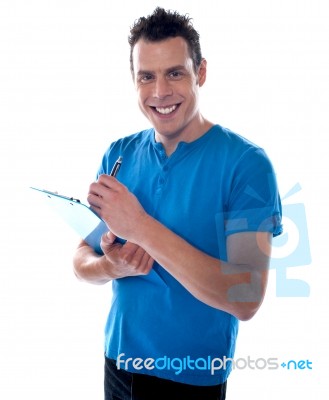 Smiling Man Writing On Clipboard Stock Photo