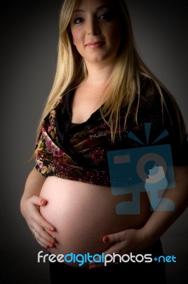 Smiling Pregnant Female Holding Her Tummy Stock Photo