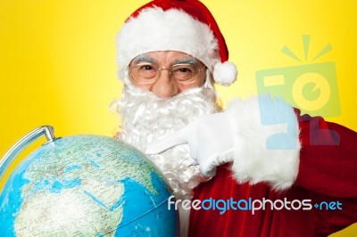 Smiling Santa Pointing At Globe Map Stock Photo