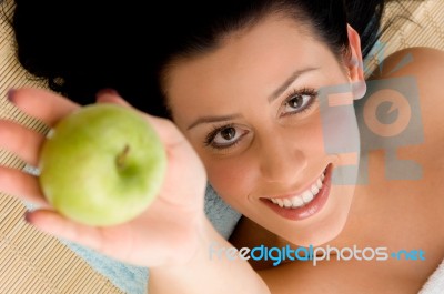 Smiling Woman Offering Apple On An Isolated Background Stock Photo