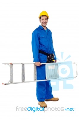 Smiling Worker Carrying A Ladder Stock Photo