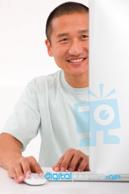 Smiling Young Asian Man Using Computer Stock Photo