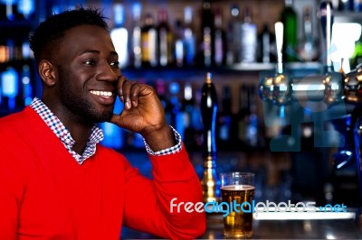 Smiling Young Guy In Bar Looking At Something Stock Photo