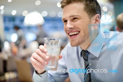 Smiling Young Man Drinking Water In Cafe Stock Photo