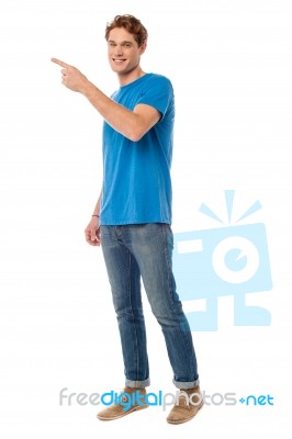 Smiling Young Man Pointing To The Side Stock Photo