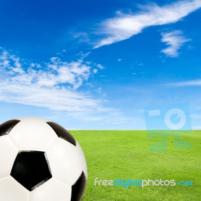 Soccer Ball With Green Grass Field Against Blue Sky Stock Photo