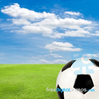 Soccer Ball With Green Grass Field Against Blue Sky Stock Photo