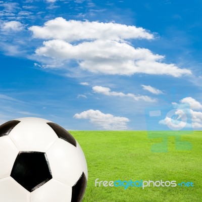 Soccer Ball With Green Grass Field Against Blue Sky Stock Photo