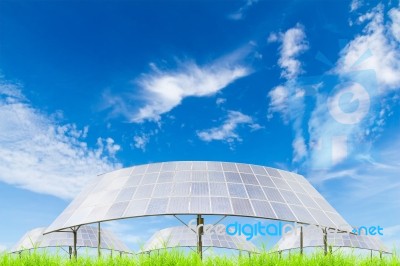 Solar Panels On Green Grass Field Against Blue Sky Background Stock Photo