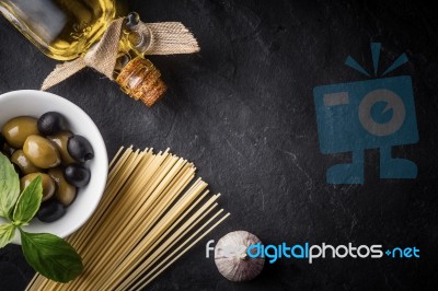 Spaghetti, Olives And Olive Oil On The Black Stone Table Stock Photo