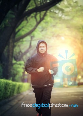 Sport Healthy Man Wearing Hood Jacket Running In Green Park Stock Photo