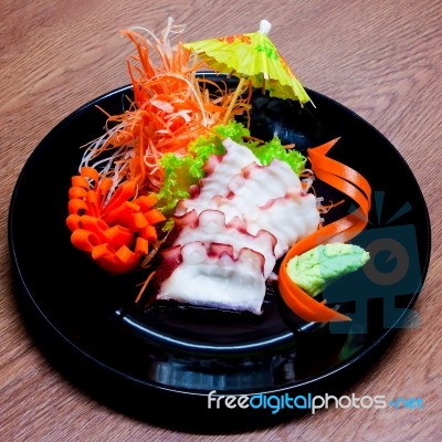 Squid Sashimi In Black Plate On Wood Table Stock Photo