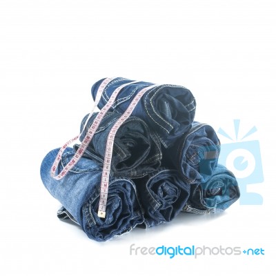 Stack Of Rolled Jeans With Tape Measure Stock Photo