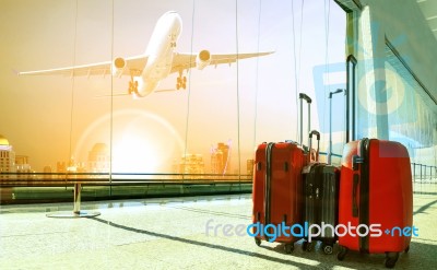 Stack Of Traveling Luggage In Airport Terminal Building And Passenger Plane Flying Over Urban Scene Stock Photo