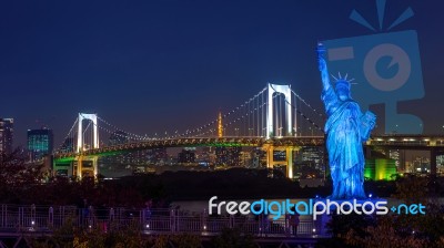 Statue And Rainbow Bridge At Night Stock Photo