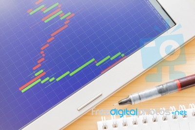 Stock Or Forex Graph Or Candlestick Chart On Blue Screen And Pen And Notebook Stock Photo