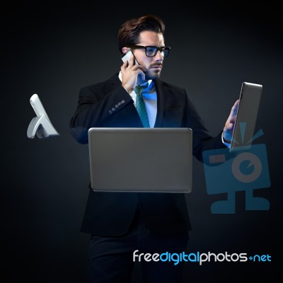 Stressed Businessman Talking On Phone Surrounded By Technology Stock Photo