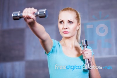 Strong Young Woman Exercising With Dumbbells At The Gym Stock Photo