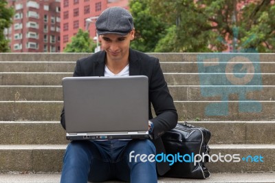 Student Working On His Laptop With An Irish Cap Stock Photo