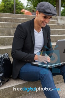 Student Working On His Laptop With An Irish Cap Stock Photo