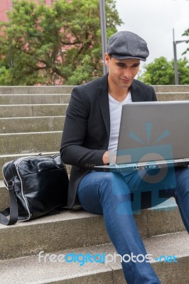 Student Working On His Laptop With An Irish Cap Stock Photo