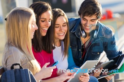 Students Having Fun With Smartphones And Tablets After Class Stock Photo