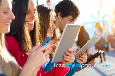 Students Having Fun With Smartphones And Tablets After Class Stock Photo