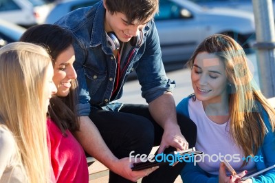 Students Having Fun With Smartphones And Tablets After Class Stock Photo