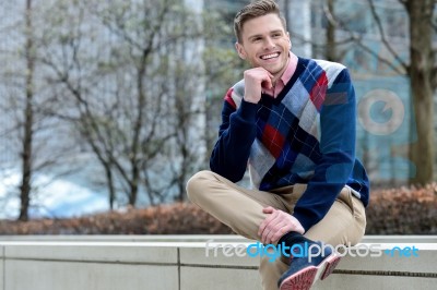 Stylish Young Man Sitting In Sidewalk Stock Photo