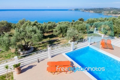 Sunloungers On Terrace With Swimming Pool Near Sea Stock Photo