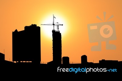 Sunset And Silhouette Construction City With Crane On Top Building Stock Photo