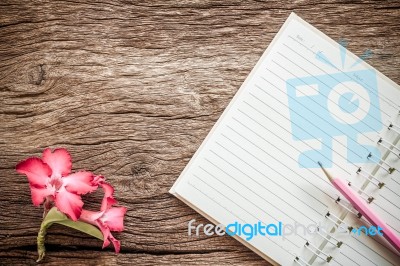 Surface Of A Wooden Table With Notebook, Desert Rose. Vintage Style Stock Photo