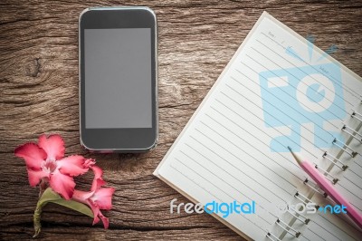 Surface Of A Wooden Table With Notebook, Smartphone, Desert Rose… Stock Photo