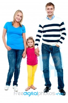 Sweet Little Kid Standing In Between Her Parents Stock Photo