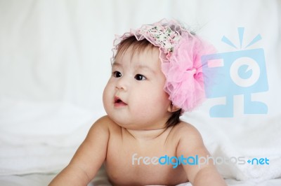 Sweet Newborn Baby In Pink Flower Hairband Lies On Bed Stock Photo